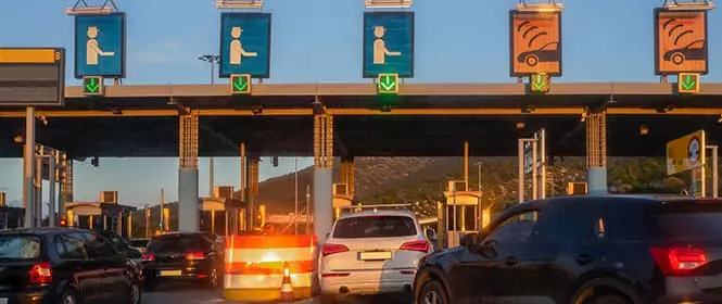 Como economizar em pedágio? Na imagem, vemos meios de transporte entrando na fila para pagar o pedágio