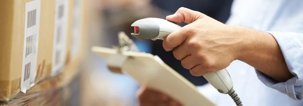 Quais empresas utilizam o cross docking? Na imagem, trabalhador lê código de barras para verificar mercadoria em transportadora, que utiliza sistema de cross docking