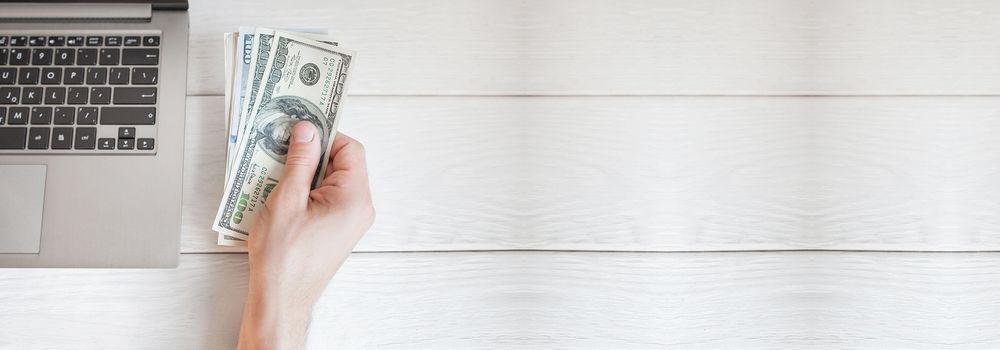 site-para-transportadora-pago-ou-gratuito Site para transportadora: Pago ou gratuito? Na imagem, notebook e notas de dinheiro em alusão às opções de criar um site gratuito ou pago, nas quais cada uma delas podem ter vantagens e desvantagens